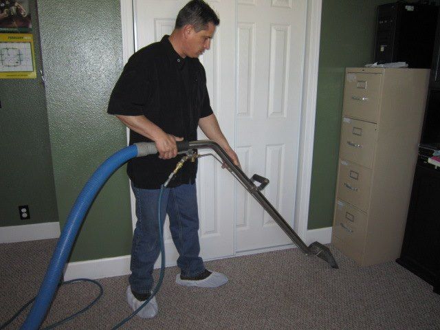 A person is cleaning a couch with a vacuum cleaner.