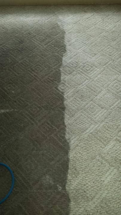A man is cleaning a carpet with a vacuum cleaner.