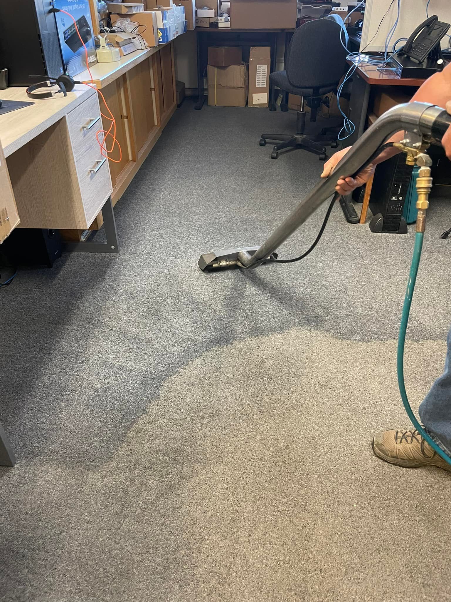 A person is holding the back of a rug on a wooden floor.