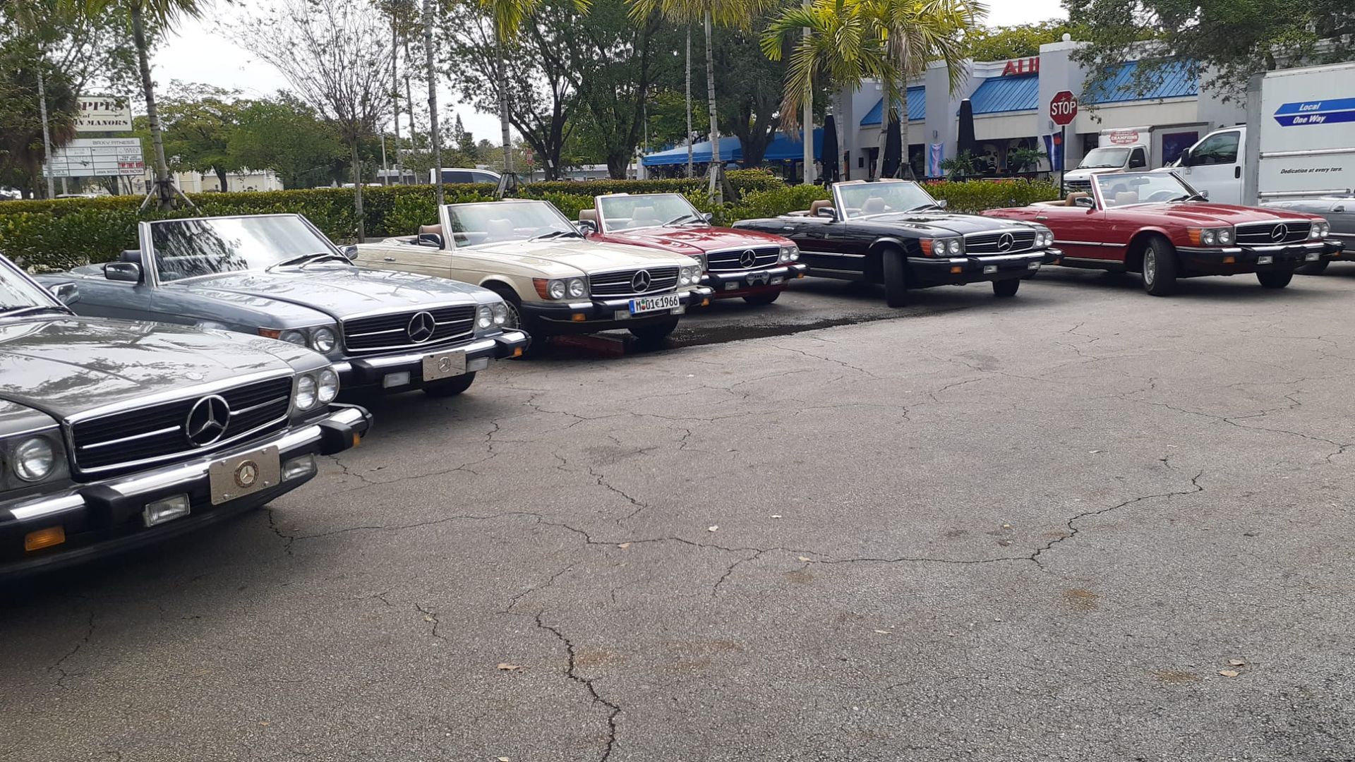 Row of classic convertibles parked outdoors on asphalt.
