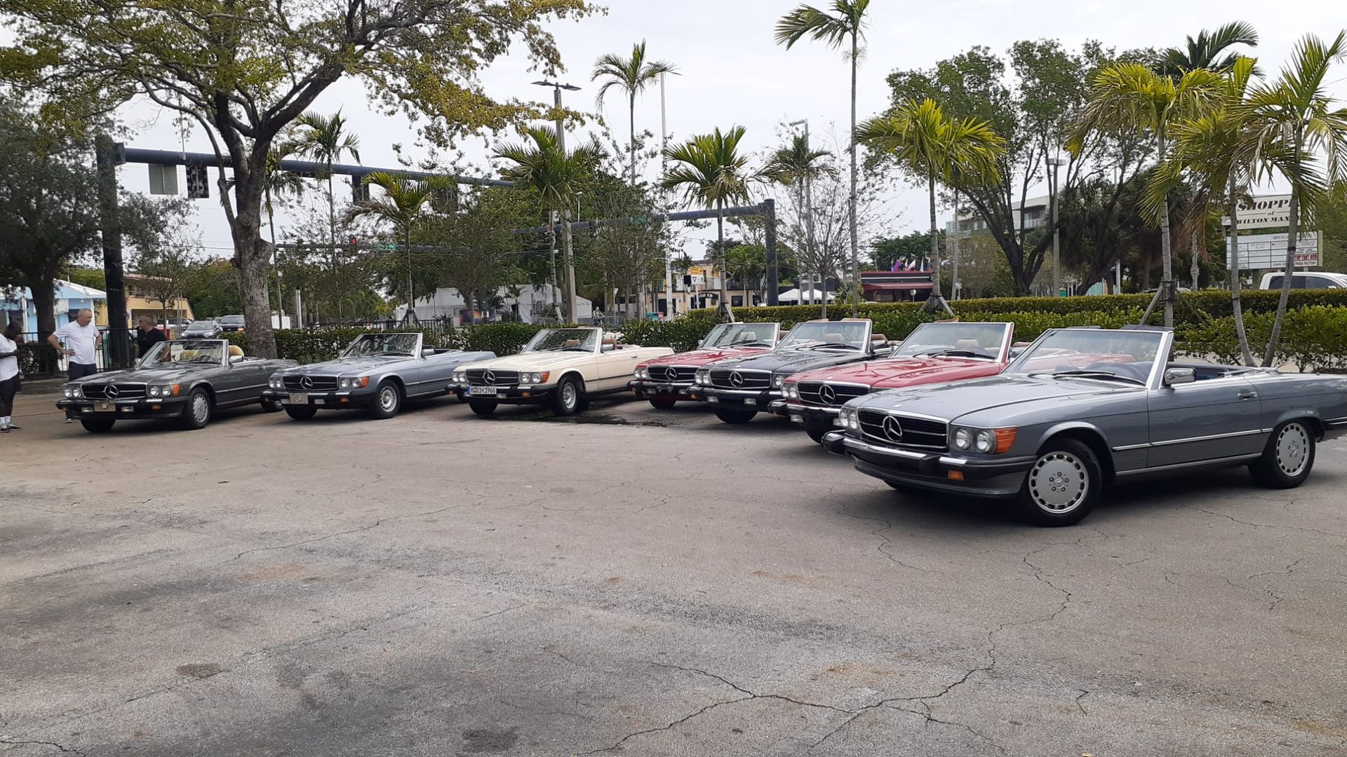 A row of classic convertible Mercedes-Benz cars parked outdoors on a cloudy day.