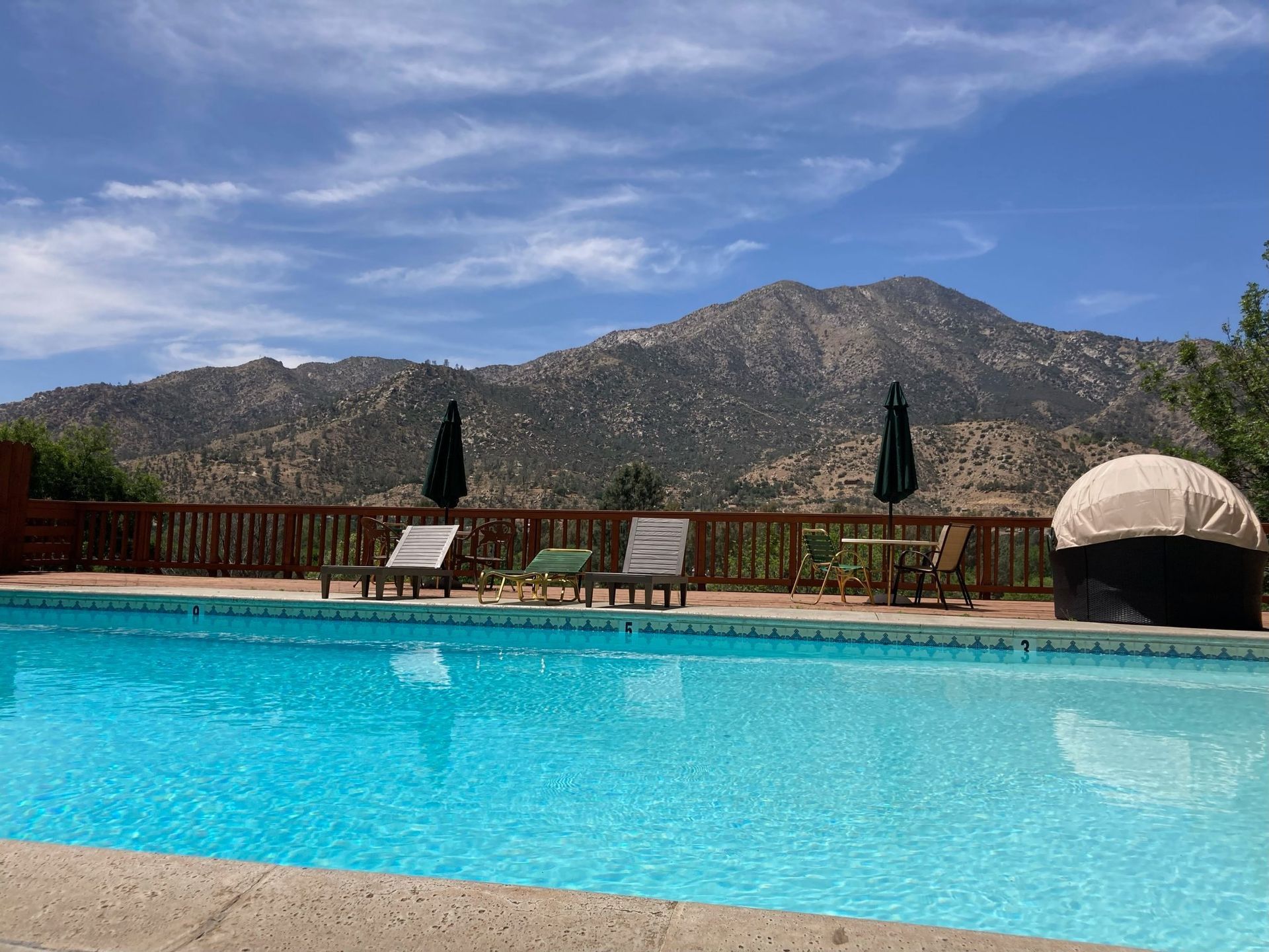 Pool with blue water and mountain backdrop under a partly cloudy sky.