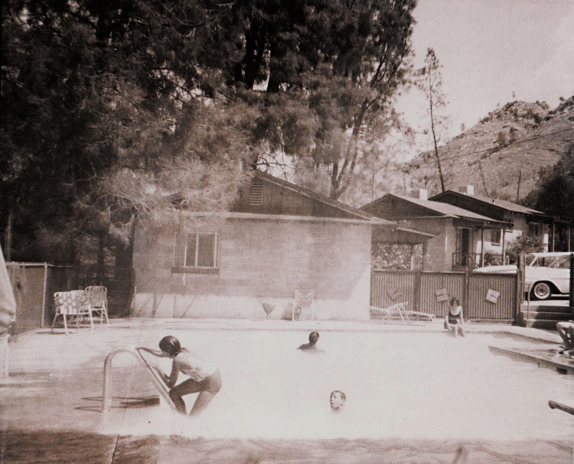 Children playing in a swimming pool with buildings and trees in the background. Vintage photo.