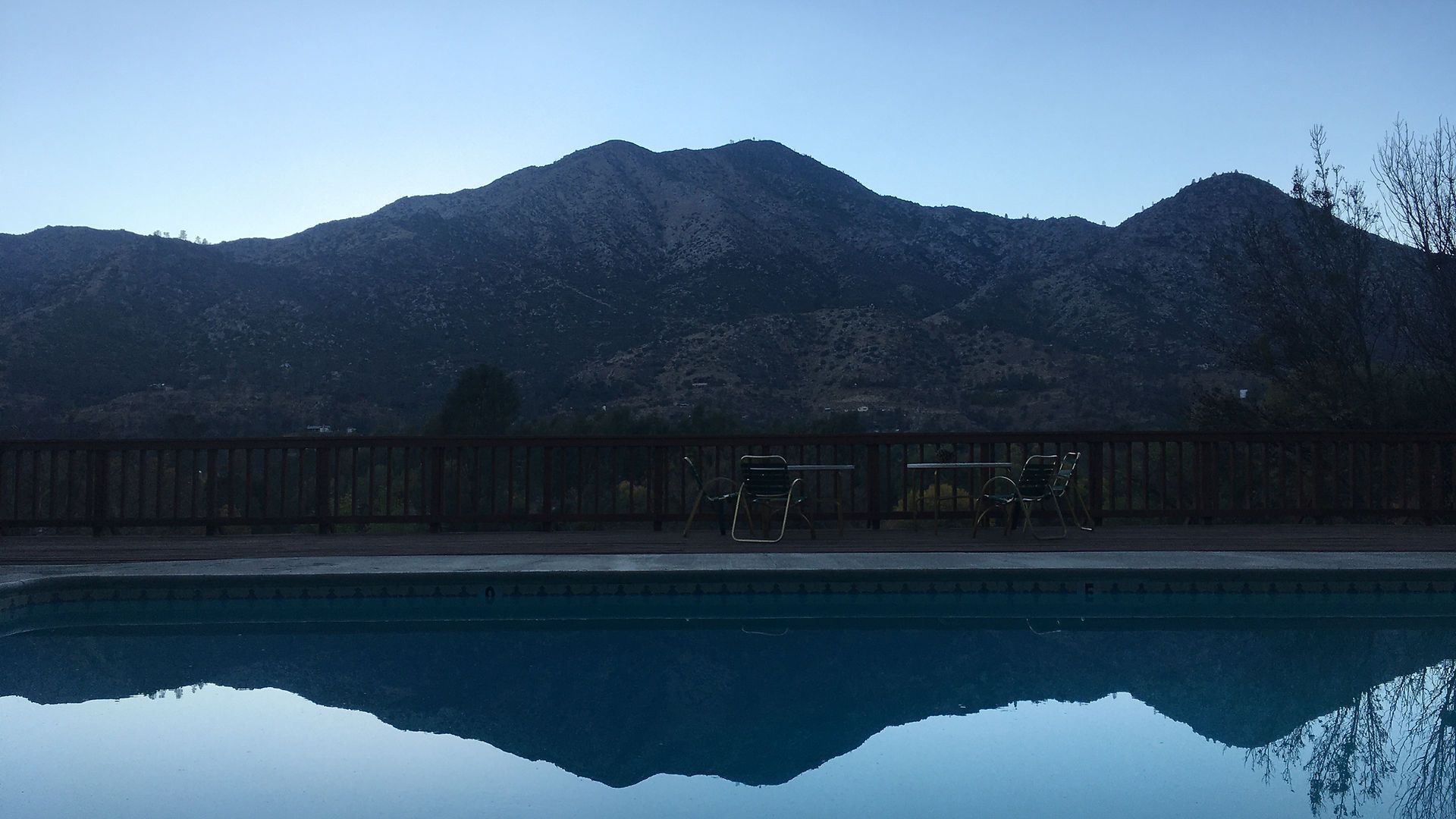 Mountain reflected in a calm pool, under a dusky blue sky.