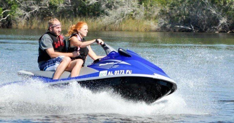 A man and a woman are riding a jet ski on a lake.
