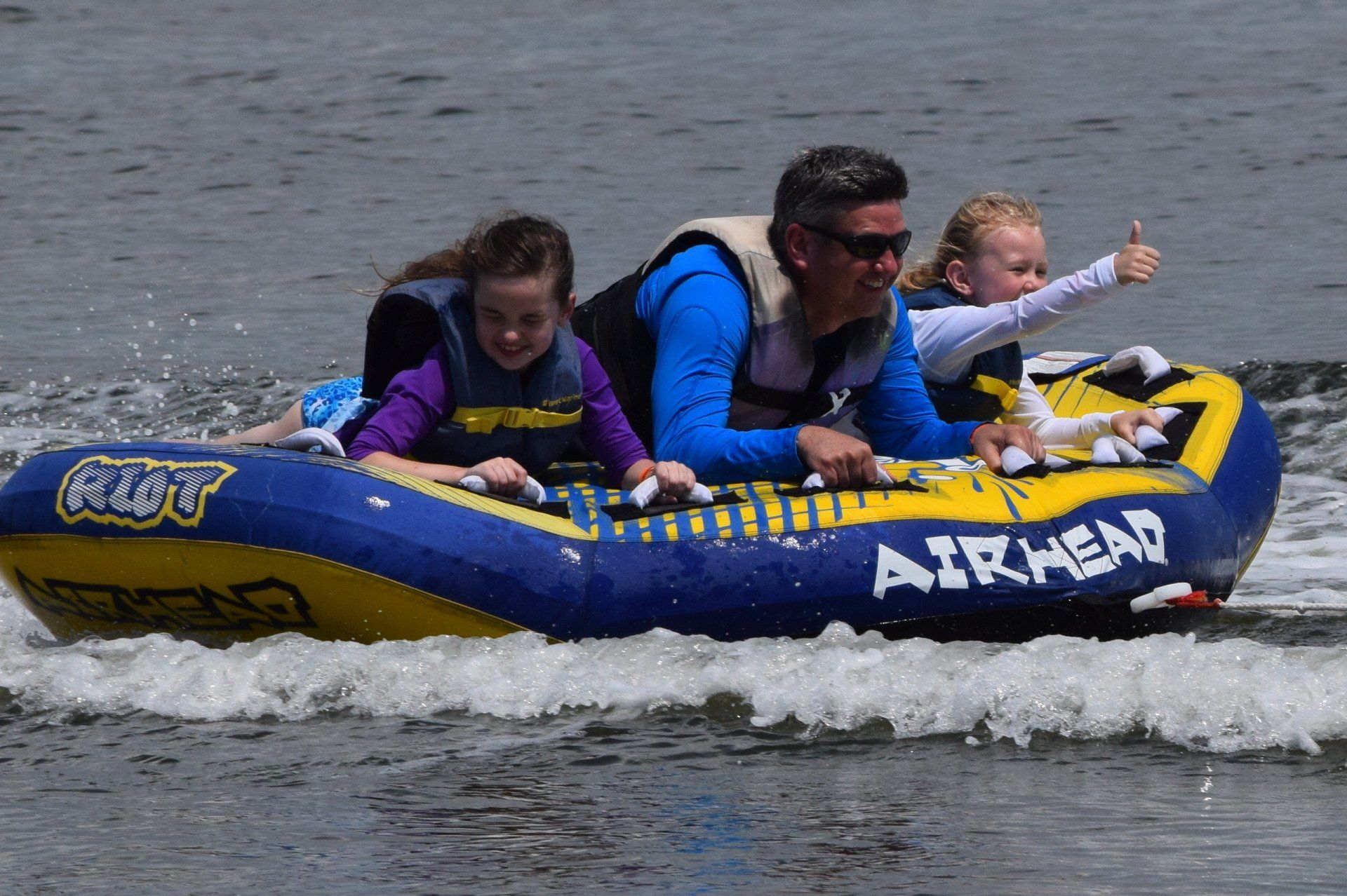 A man and two children are riding a raft in the water.