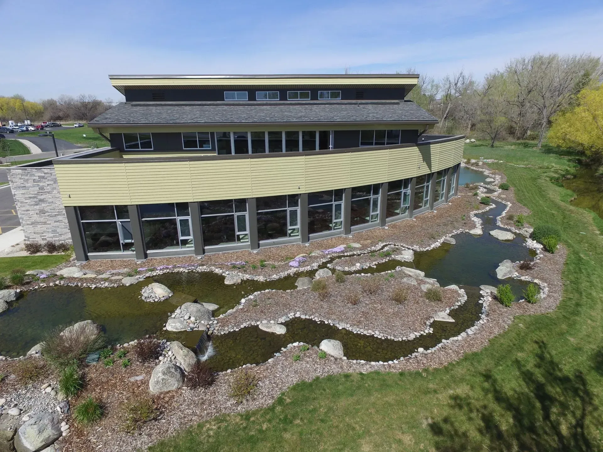 An aerial view of a large building with a pond in front of it.