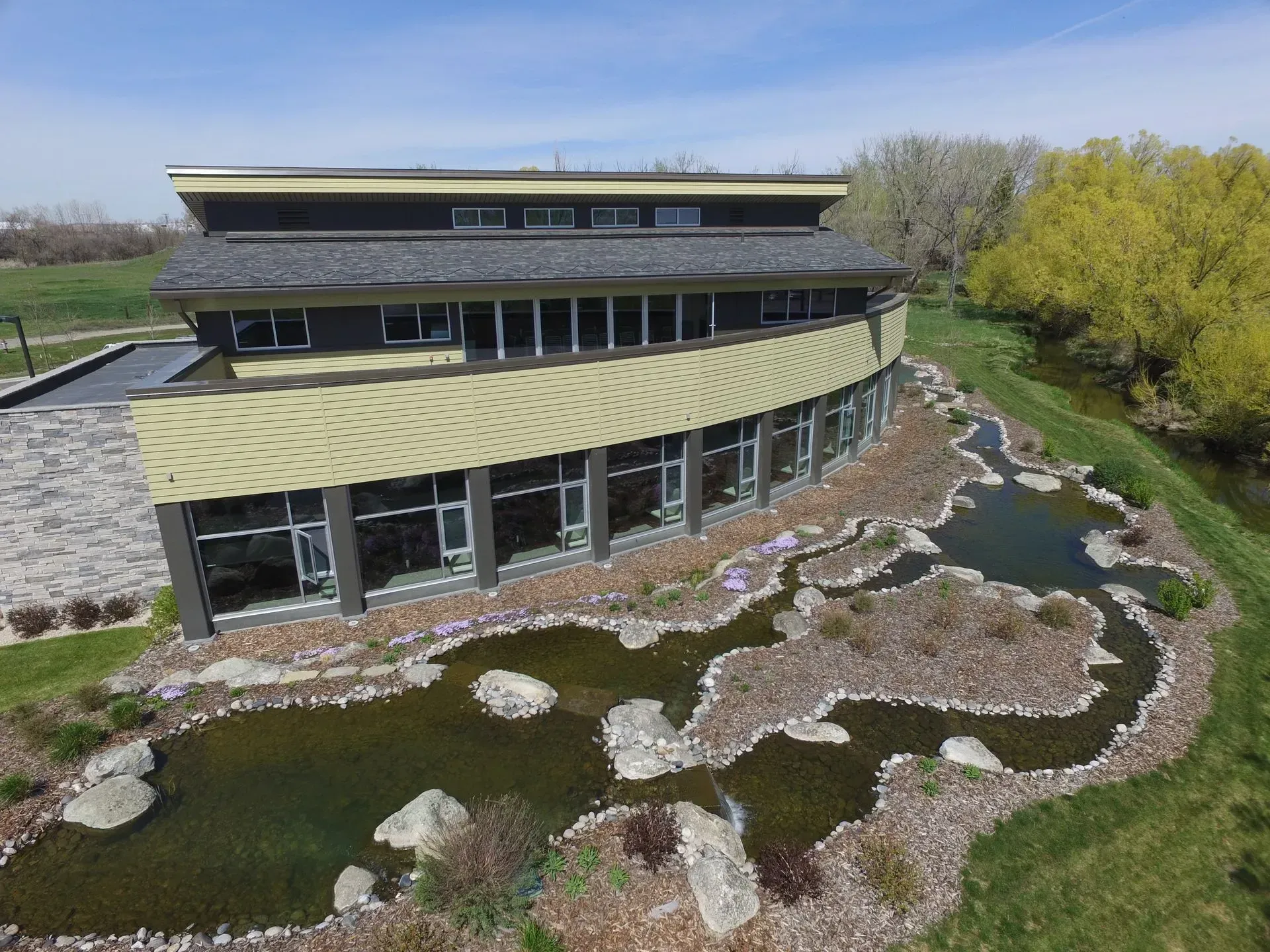 An aerial view of a large building with a pond in front of it.