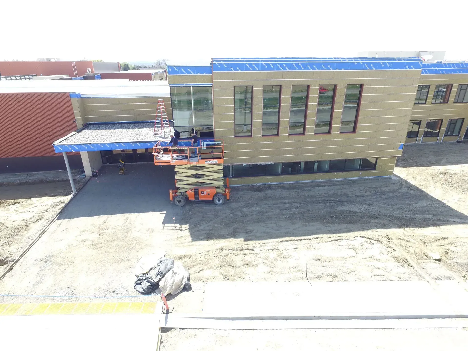 An aerial view of a building under construction with a scissor lift in front of it.