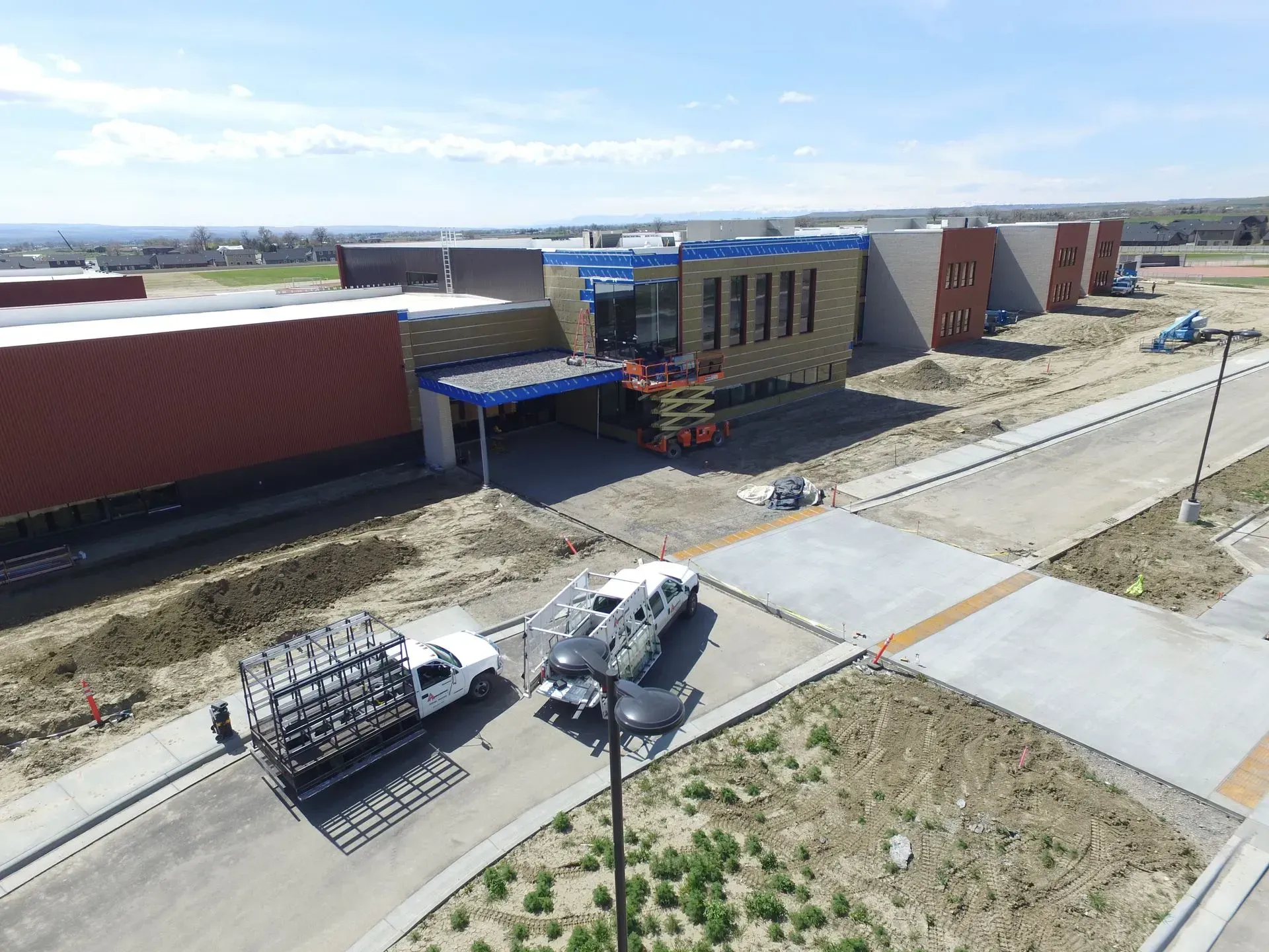 An aerial view of a building under construction with trucks parked in front of it.