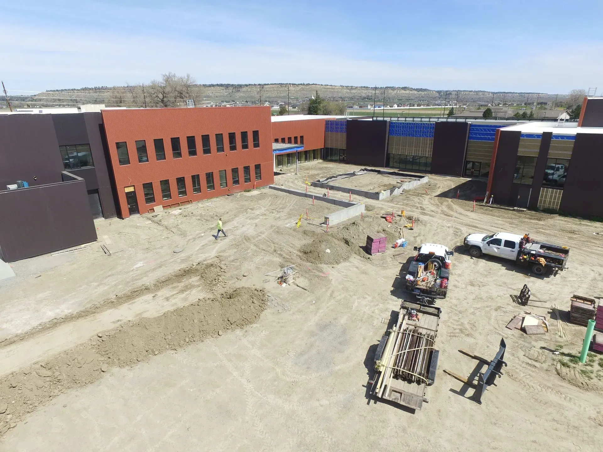 An aerial view of a building under construction with trucks parked in front of it.