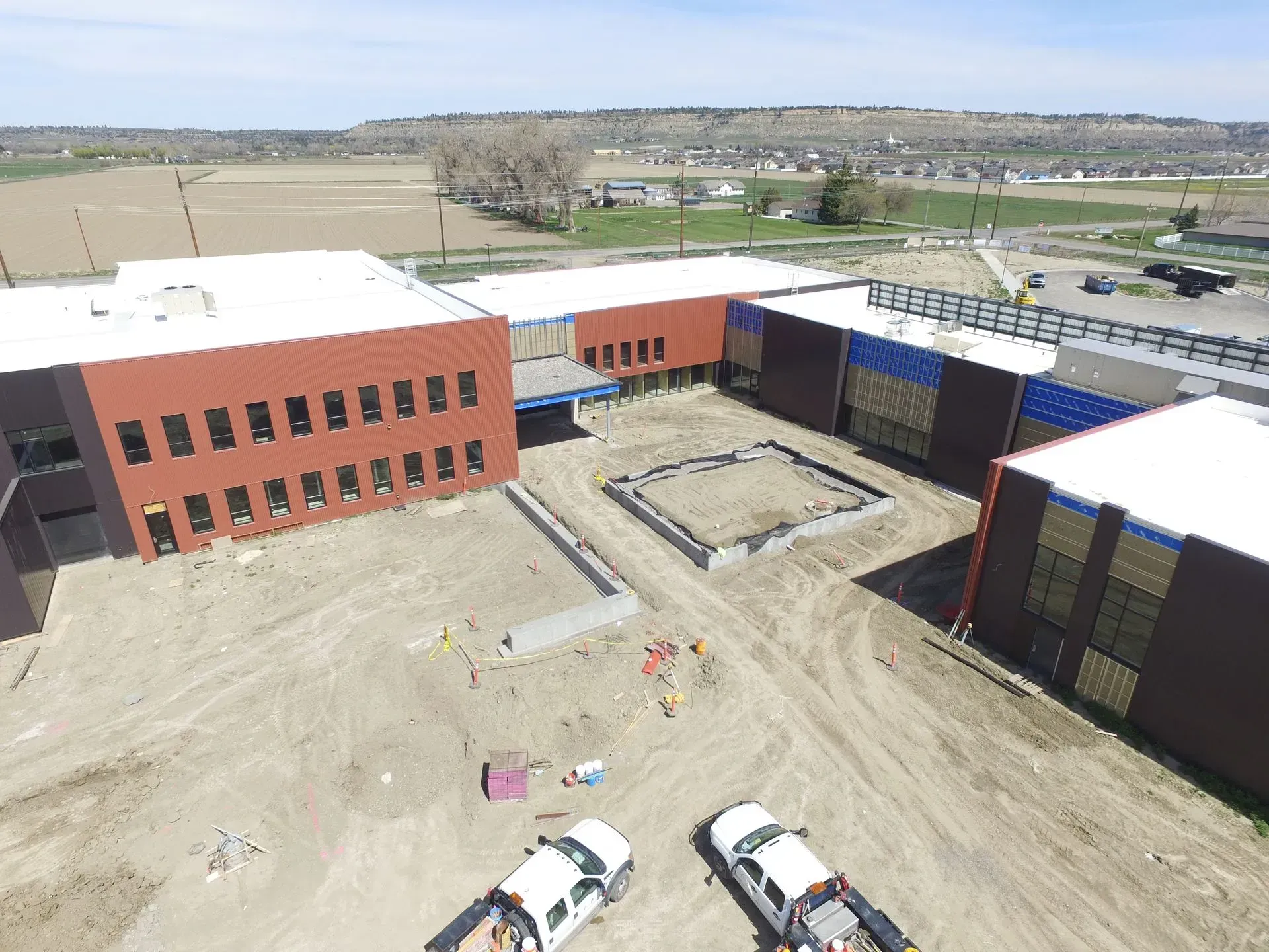An aerial view of a building under construction with trucks parked in front of it.