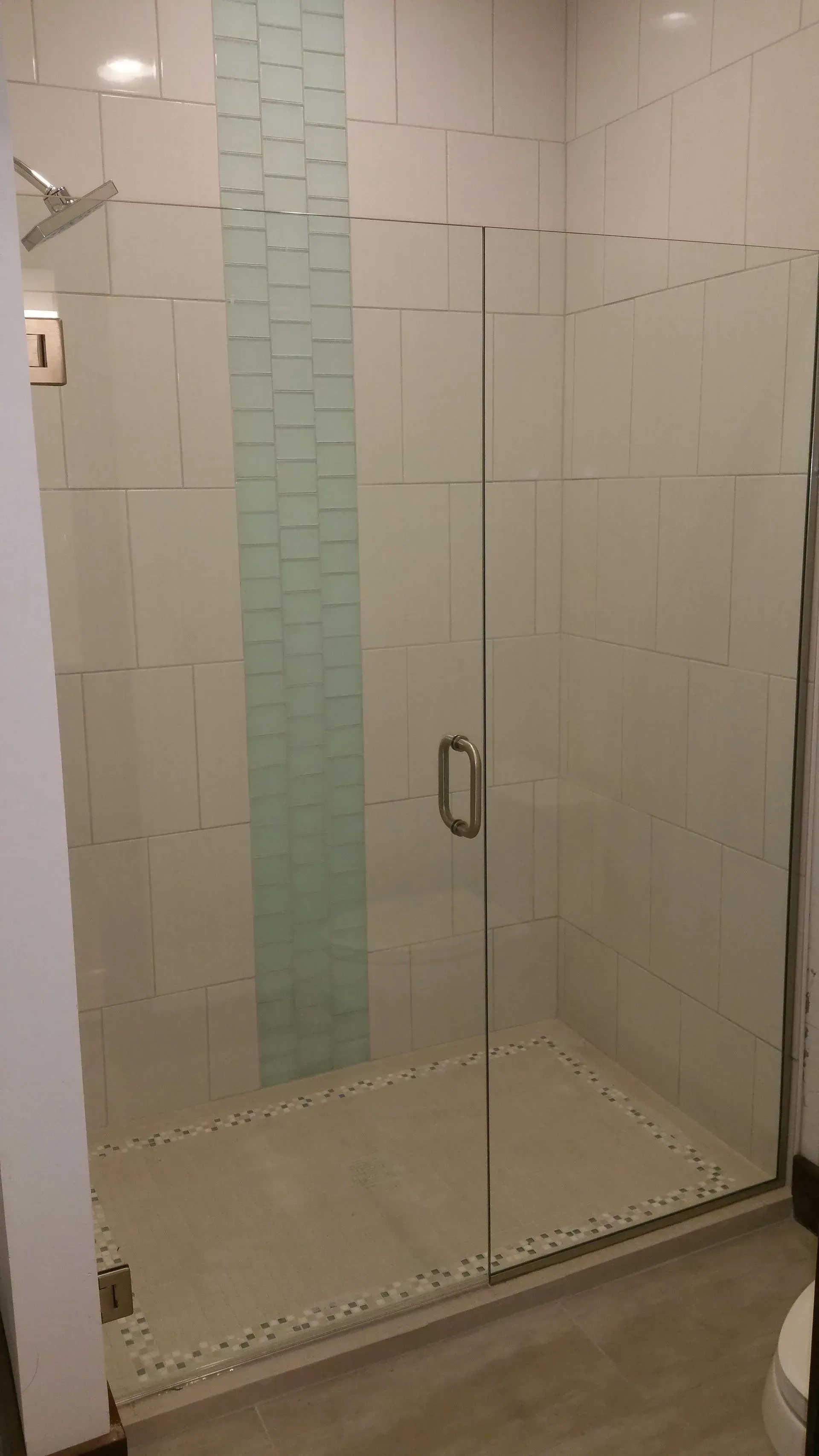 A bathroom with a walk in shower with a glass door.