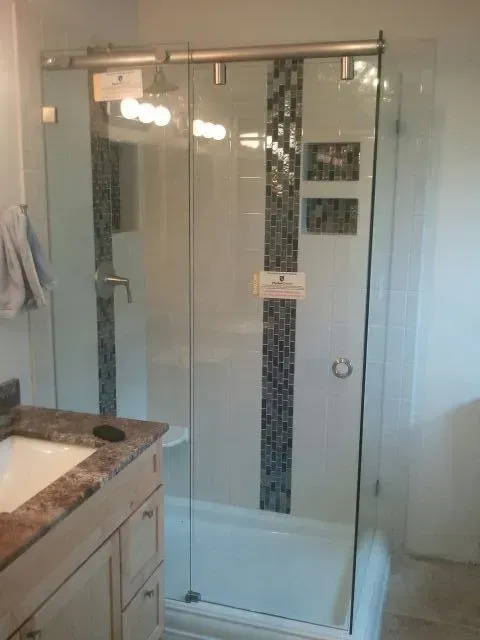 A bathroom with a sliding glass shower door and a sink