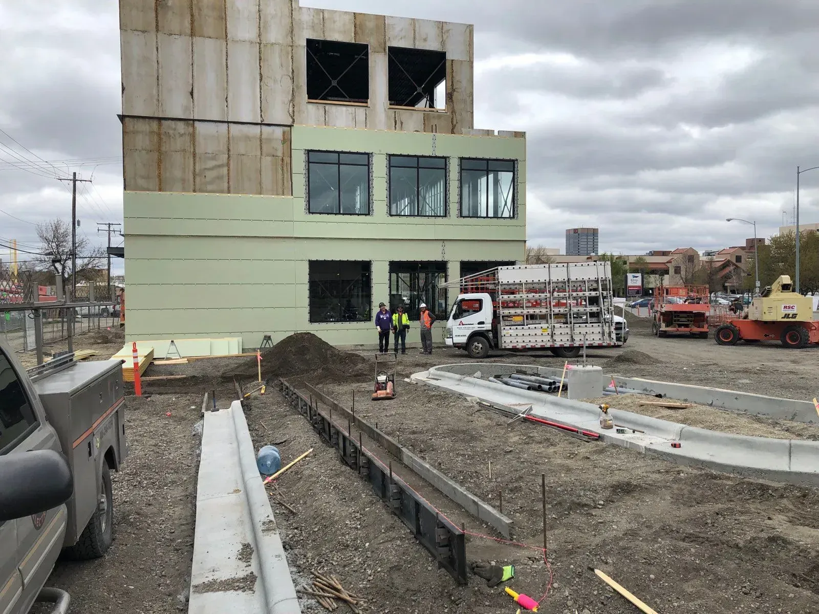 A construction site with a truck parked in front of a building under construction.
