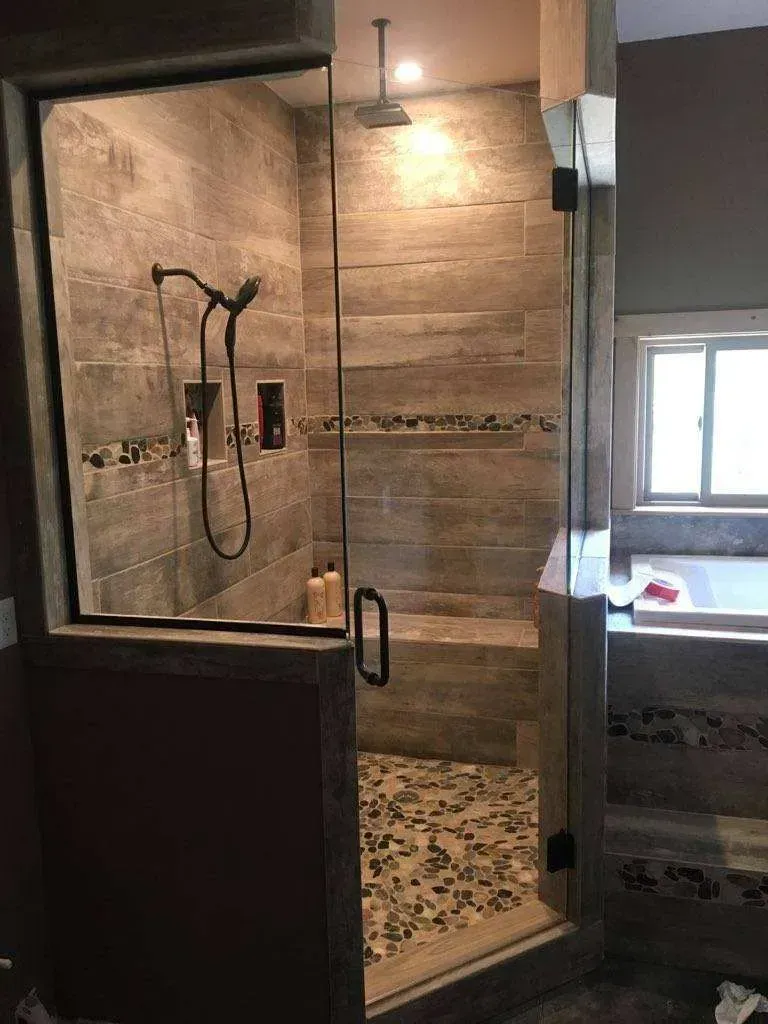 A bathroom with a walk in shower with a glass door.