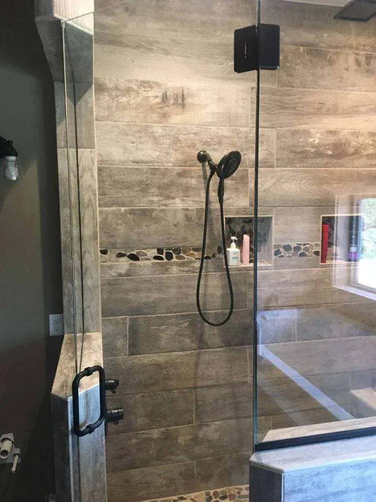 A bathroom with a walk in shower with a glass door.