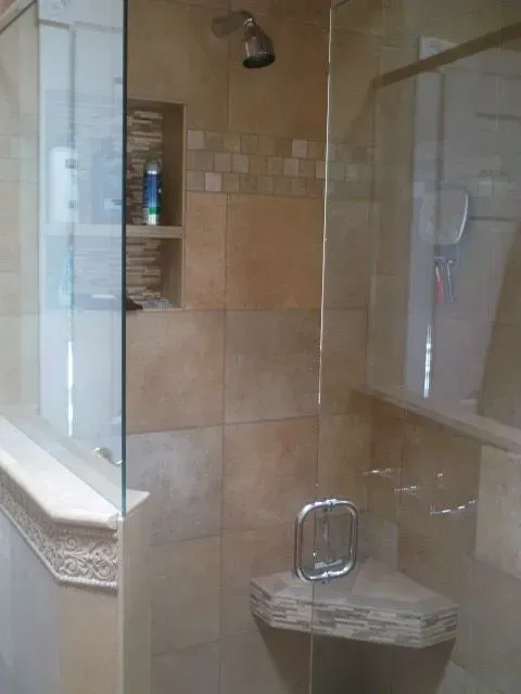 A bathroom with a walk in shower with a glass door