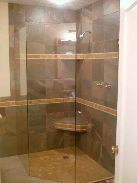 A bathroom with a walk in shower with a glass door