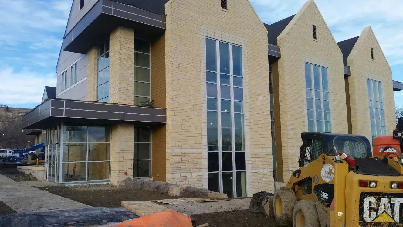 A cat skid steer is parked in front of a building under construction
