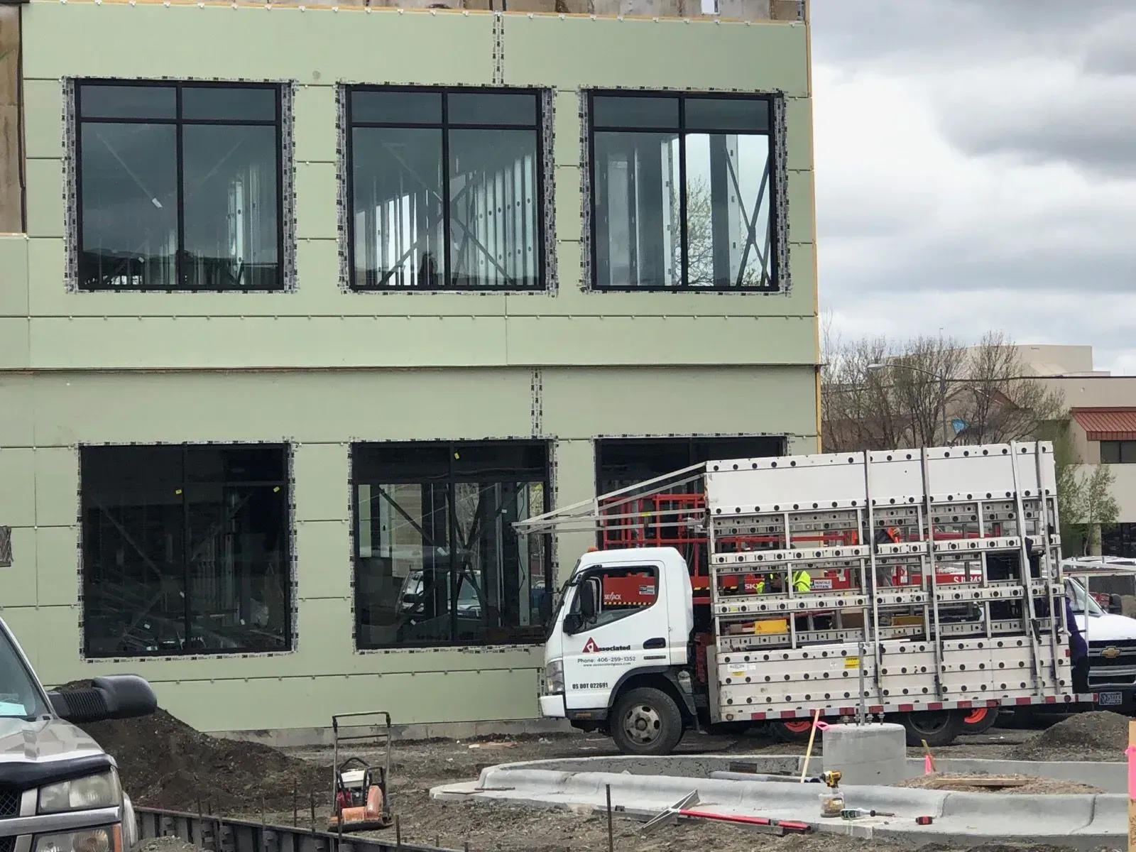 A white truck is parked in front of a building under construction.