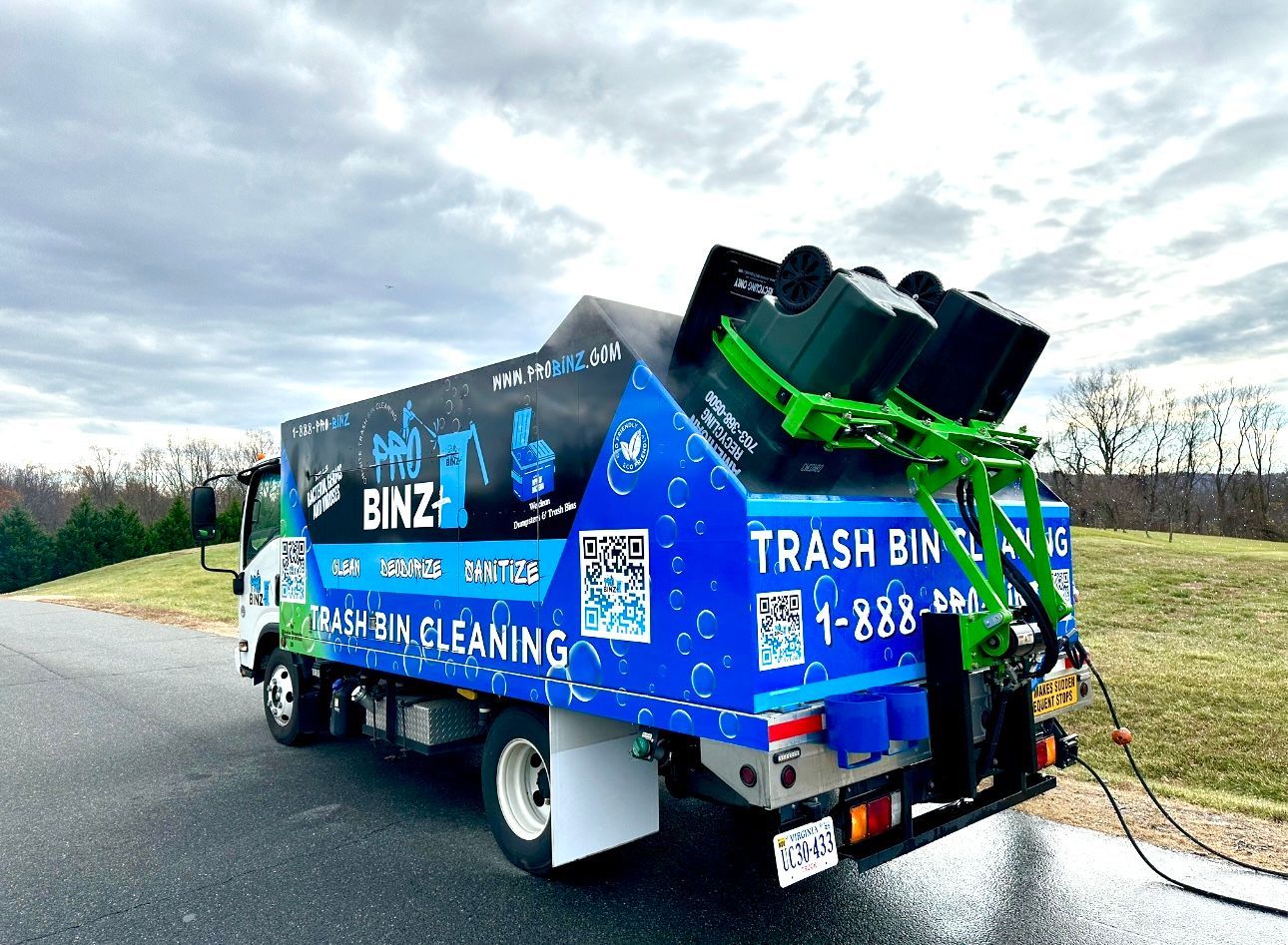 A blue trash bin cleaning truck is parked on the side of the road.