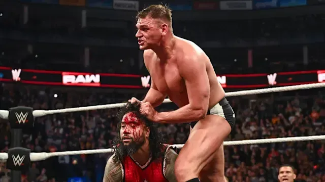 A man without a shirt is standing in a wrestling ring.