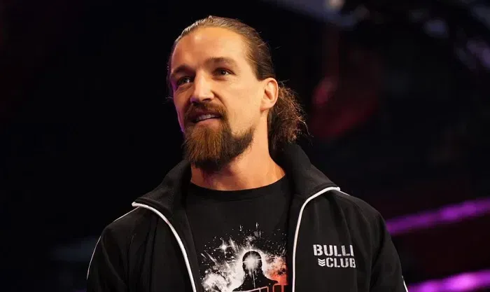 A man with a beard is wearing a black shirt and a black jacket.