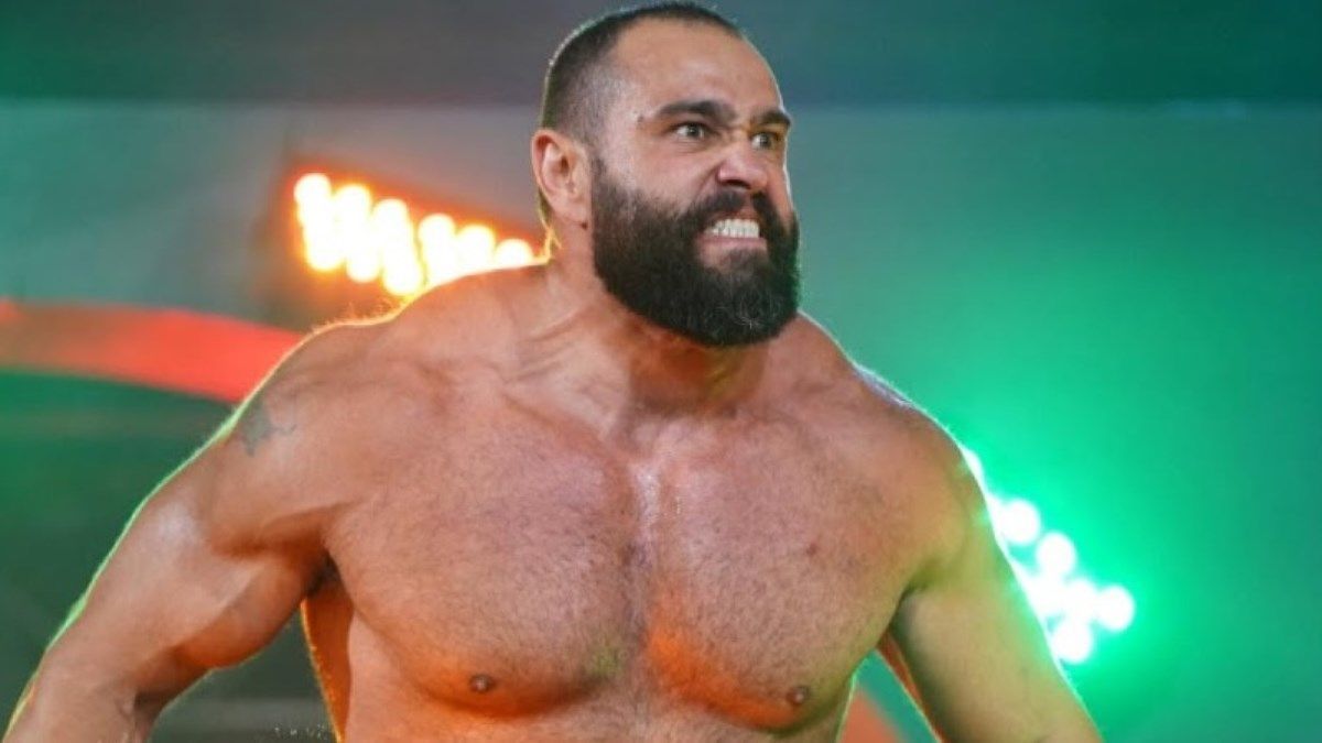 A shirtless wrestler with a beard is standing in a ring.