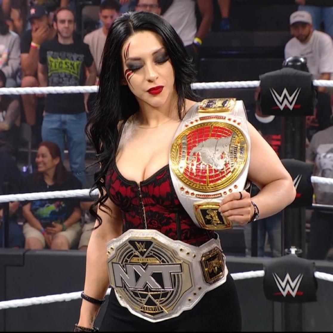 A woman in a wrestling ring holding a nxt championship belt