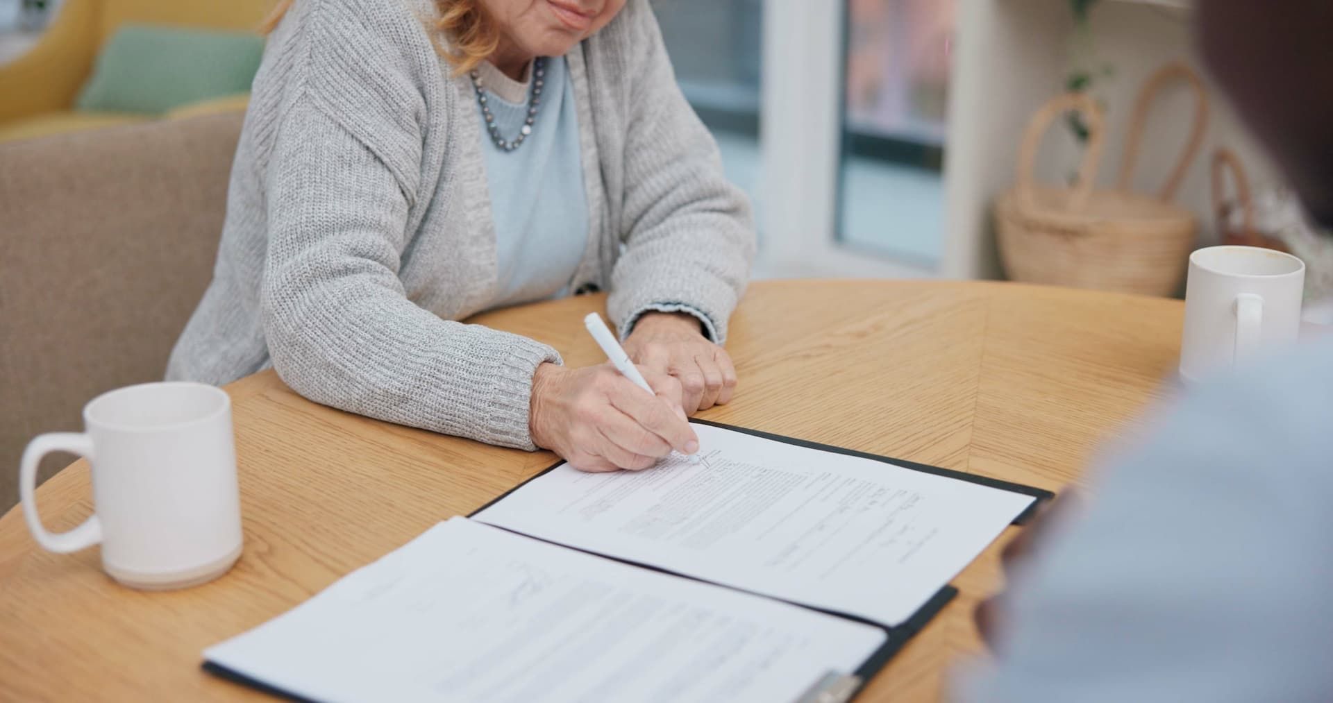 Couple reviews documents and laptop at a table, woman touches man's shoulder.