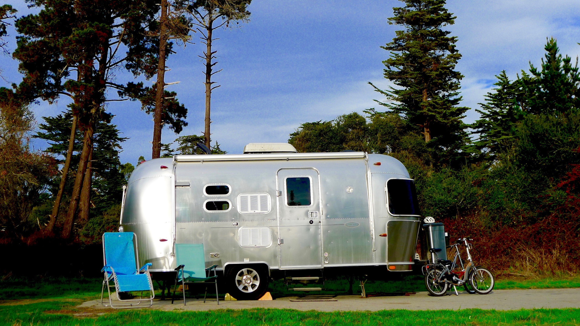 A silver airstream trailer is parked in a grassy field