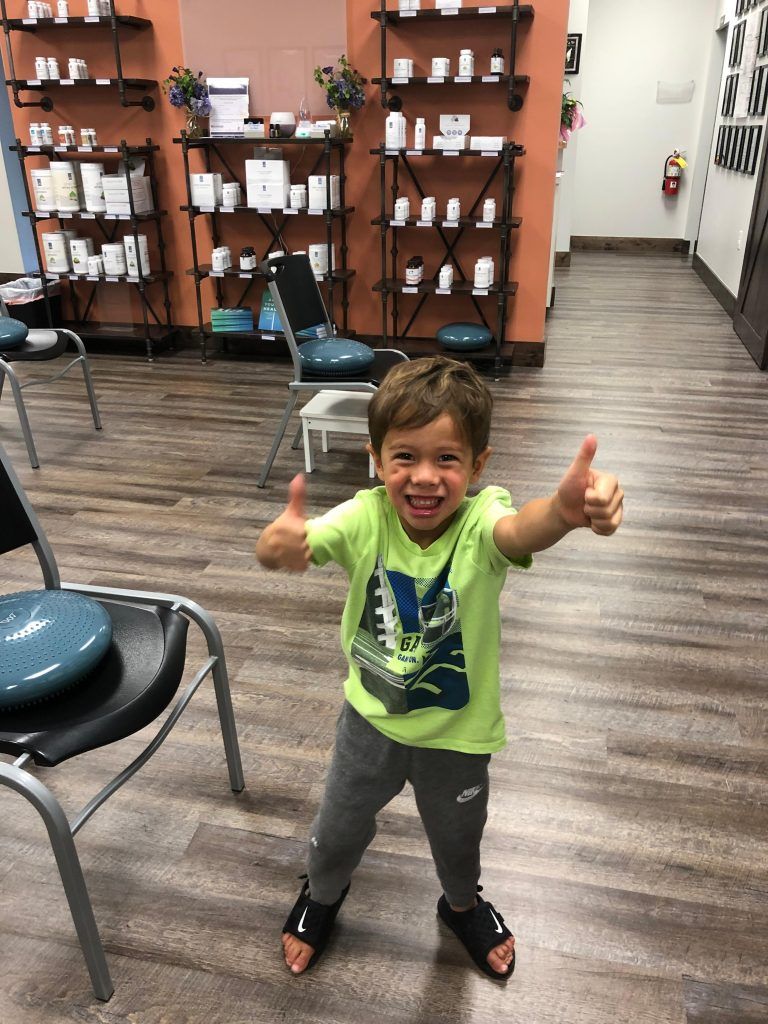 A little boy is giving a thumbs up in a waiting room.
