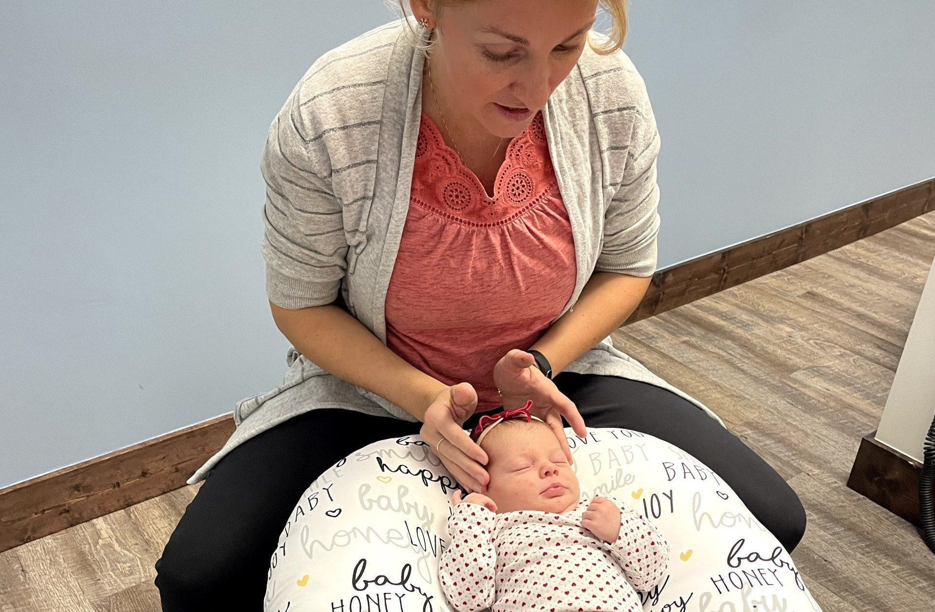 A woman is sitting on a pillow with a baby on it.