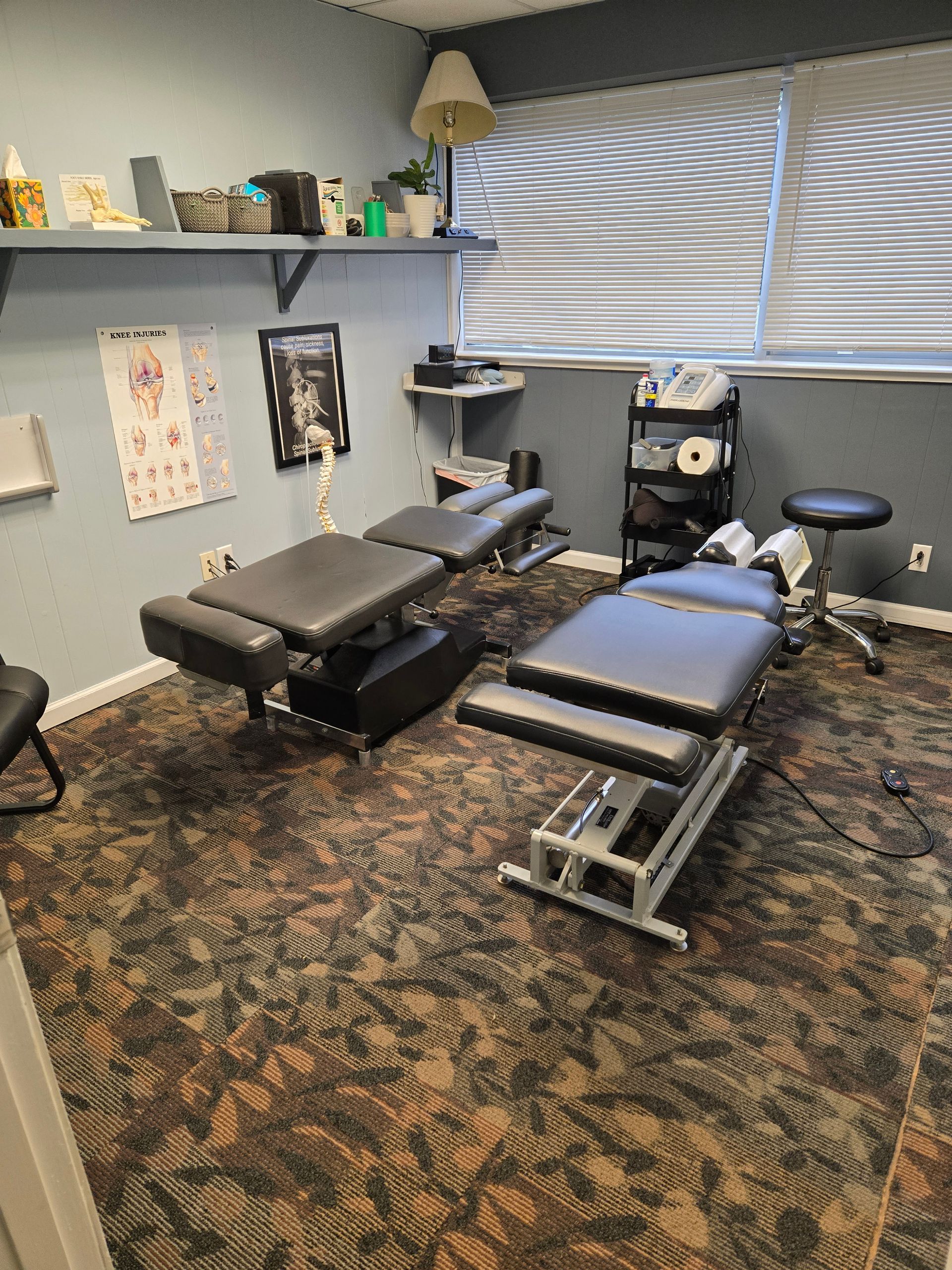 Chiropractic office with two adjustable tables, examination equipment, and storage.