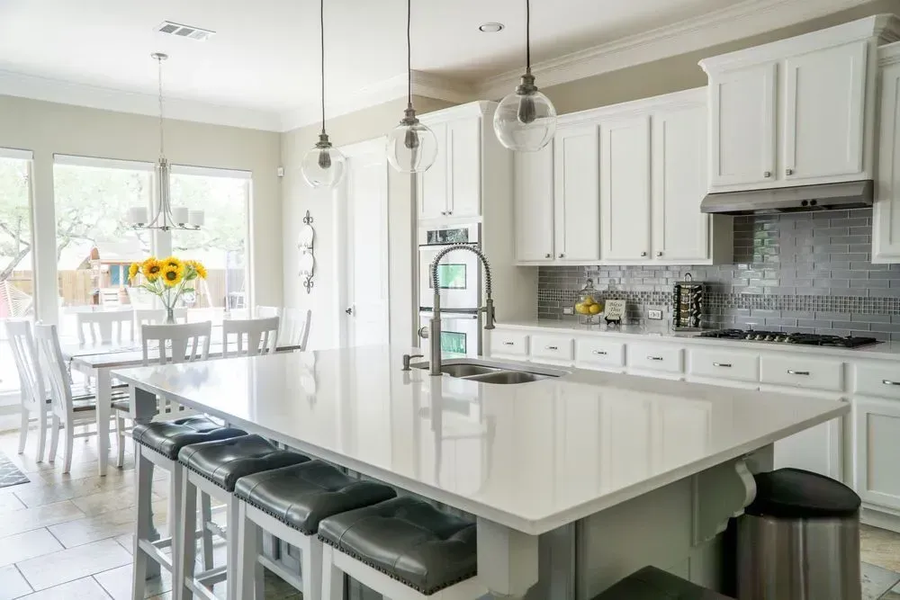White kitchen with island, breakfast nook, and cabinets; stainless steel accents.
