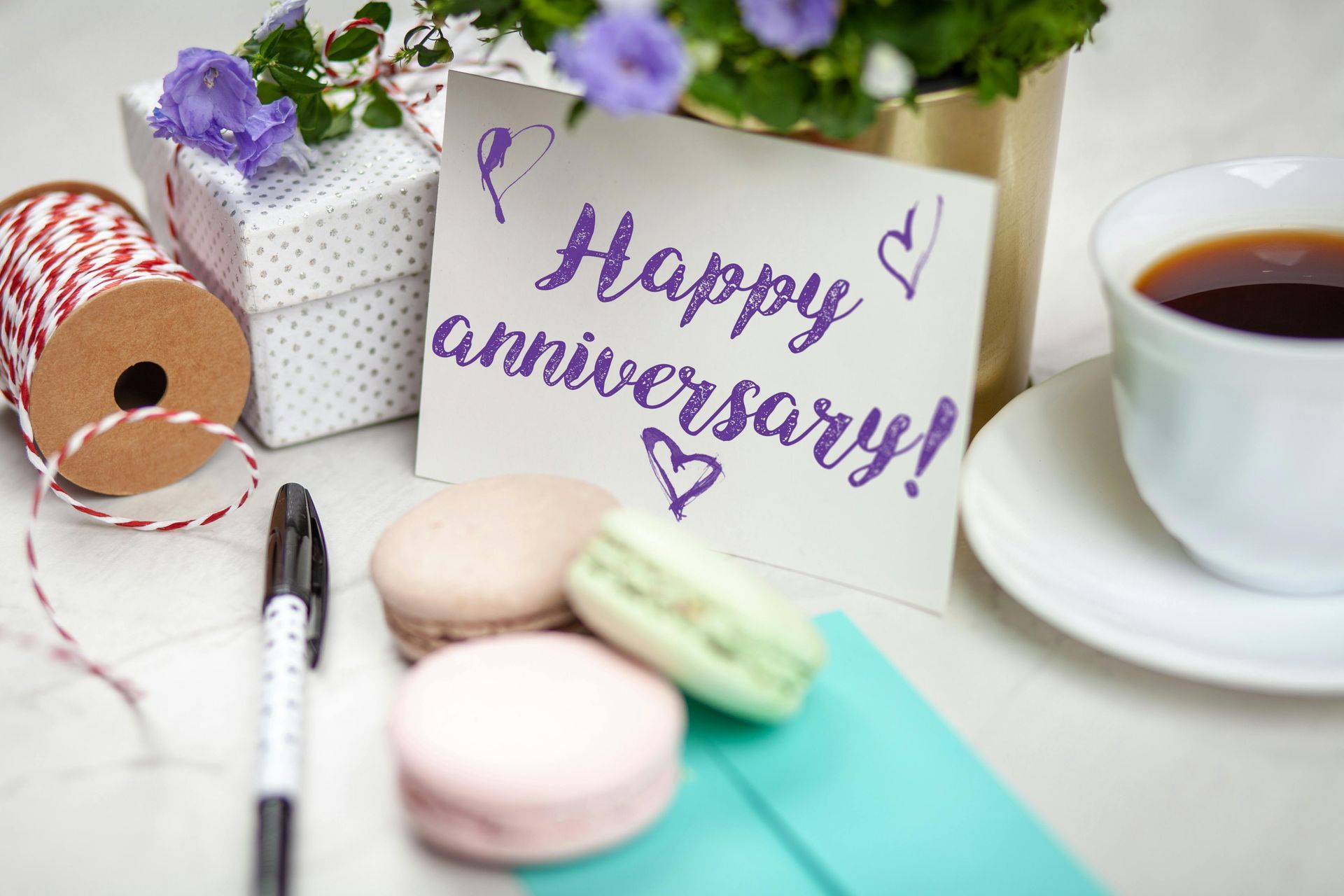 A happy anniversary card is sitting on a table next to a cup of coffee.