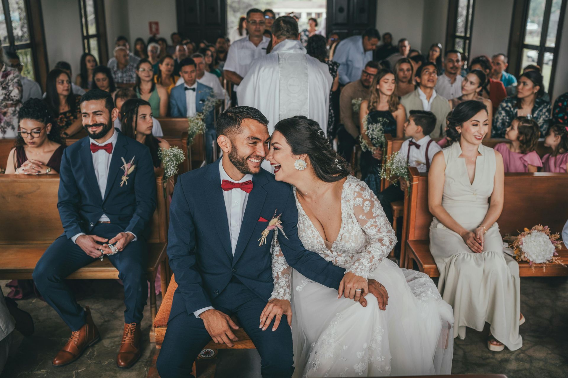 A bride and groom are sitting in a church during their wedding ceremony.