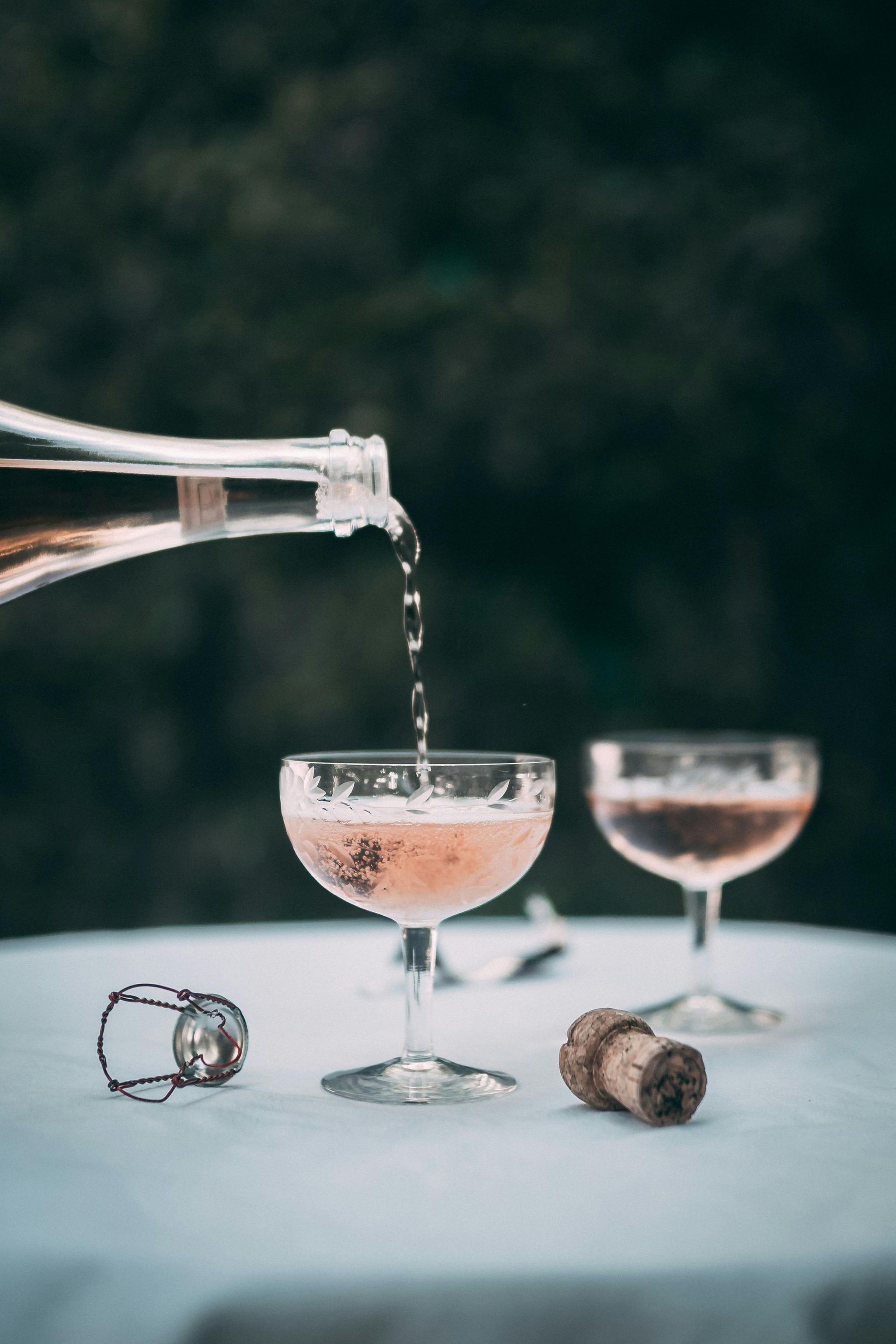 A bottle of champagne is being poured into a glass on a table.