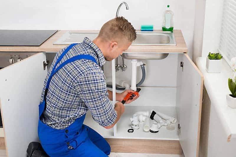 Stevenage plumber repairing a leaking kitchen sink under the counter