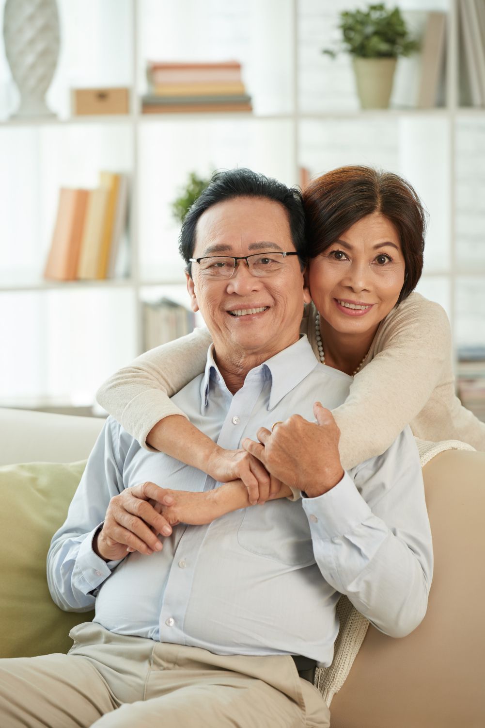 A woman is hugging a man while sitting on a couch.