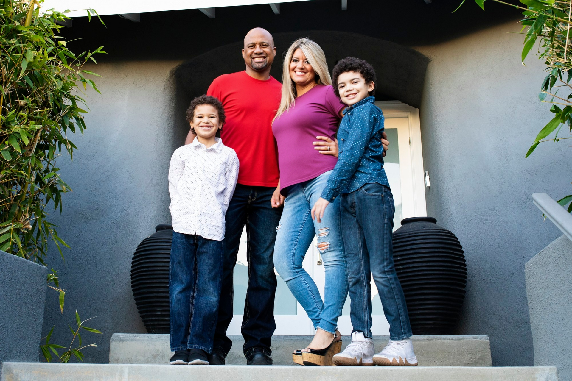 A family is posing for a picture in front of their house.