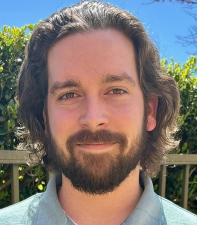 A man with long hair and a beard is smiling for the camera.