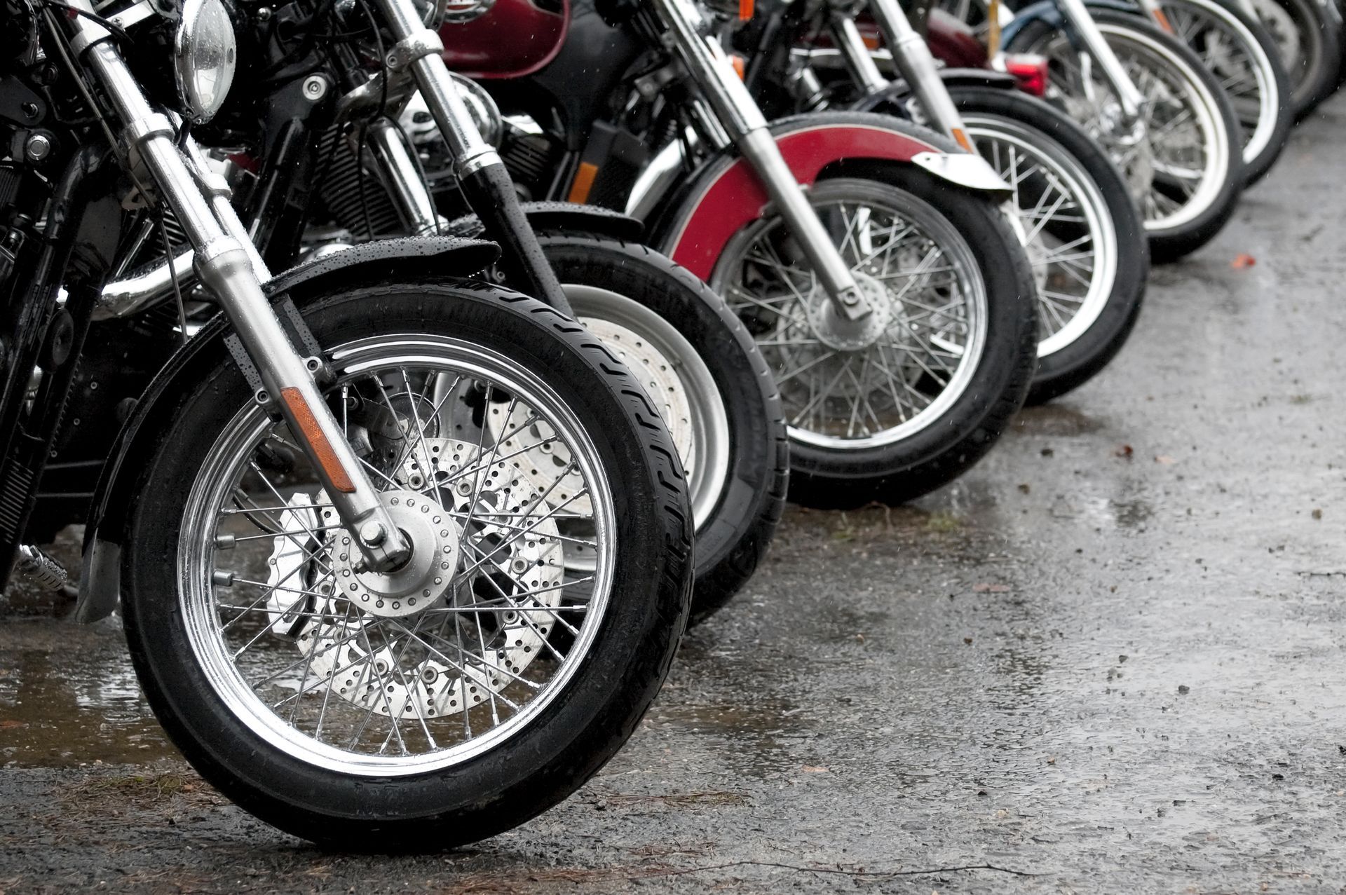 A row of motorcycles are parked in a parking lot.