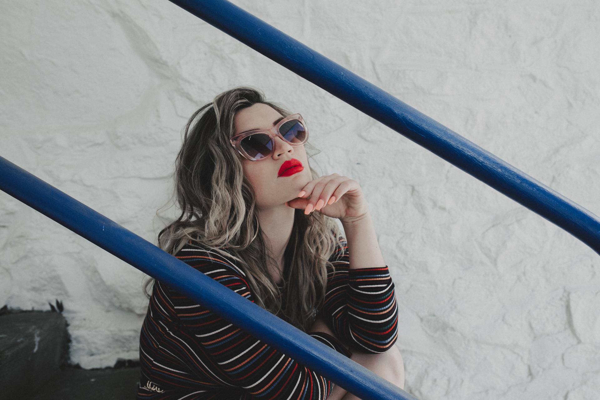 Woman in sunglasses and red lipstick sitting on steps