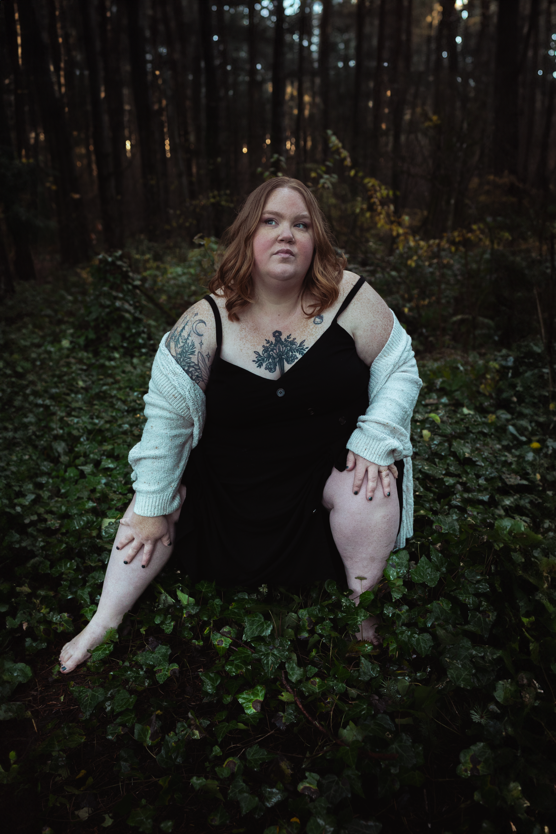 Woman sitting in forest among ivy