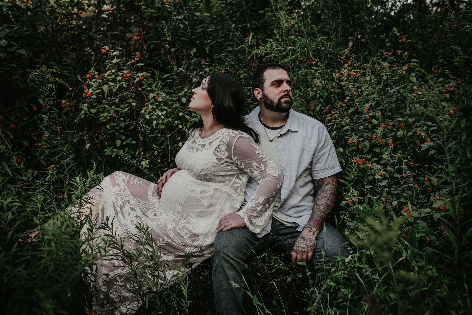 Pregnant couple sitting in flowers