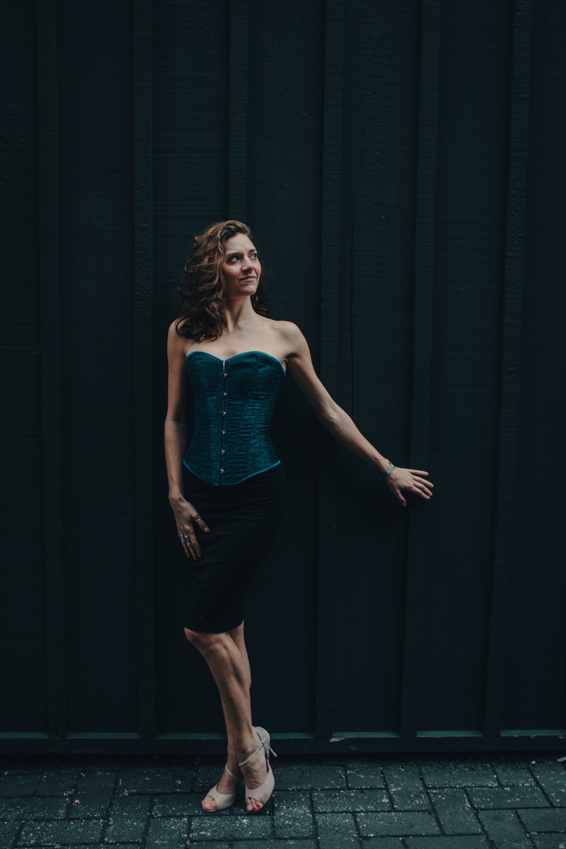 Woman in blue corset against wall