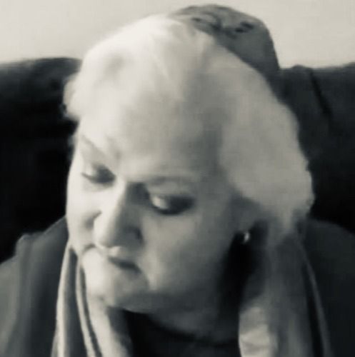 Woman with white hair, looking down, in black and white.