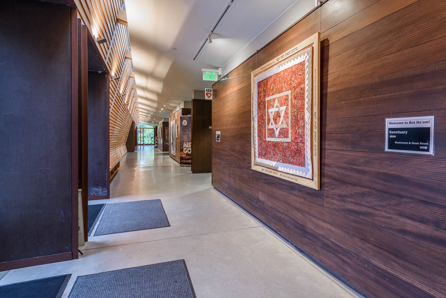 Hallway with wood paneling, artwork, and exit sign.